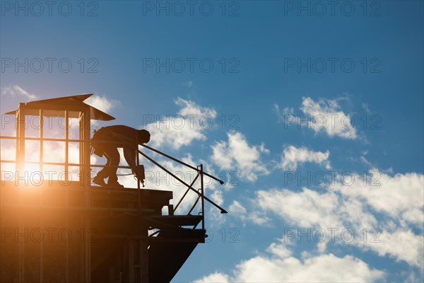 Construction workers silhouette on roof of building