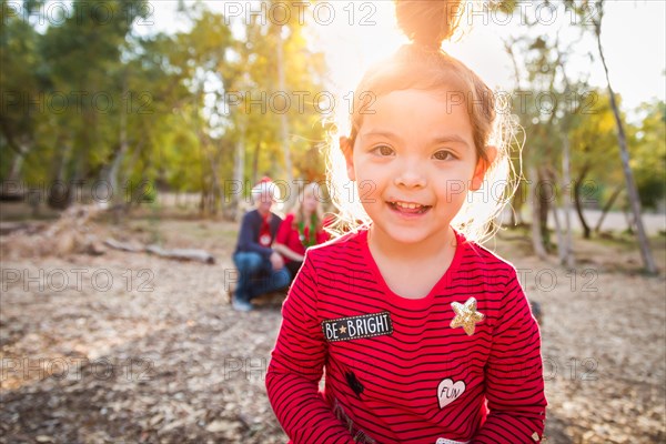 Cute mixed-race baby girl christmas portrait with family behind outdoors