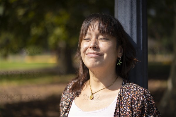 Portrait of a young Latin woman in a park leaning on a lamppost