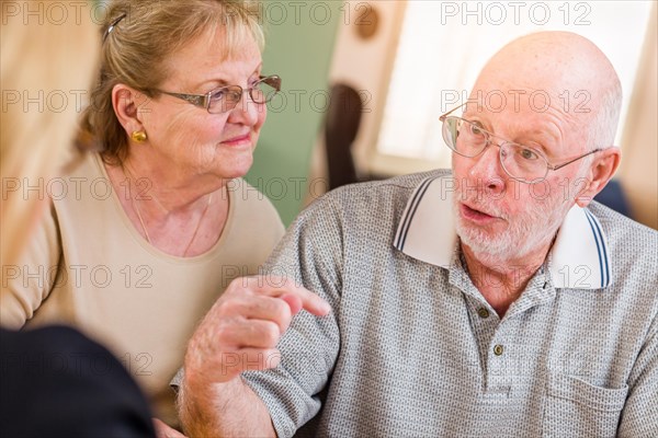 Senior adult couple going over documents in their home with agent at signing