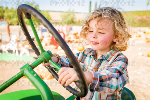 Little boy having fun in A tractor in a rustic ranch setting at the pumpkin patch