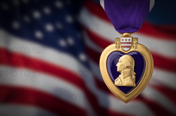 Purple heart miltary merit medal against darkened american flag