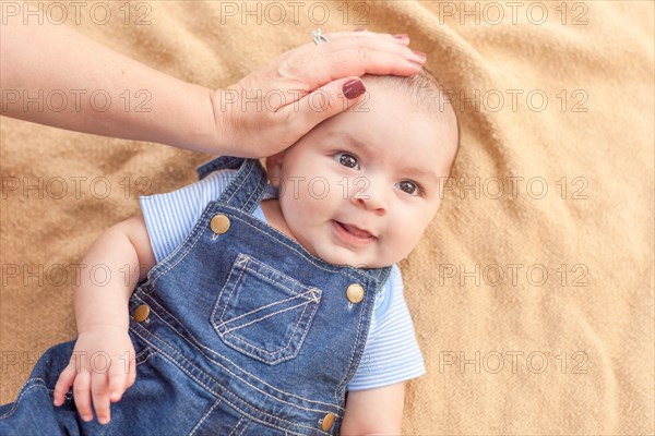 Happy mixed-race baby boy laying on blanket