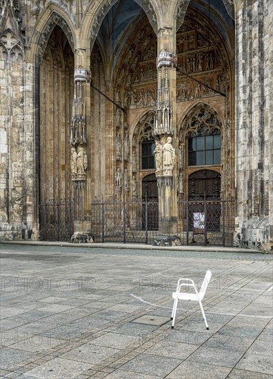 White single chair standing in front of the portal of the cathedral