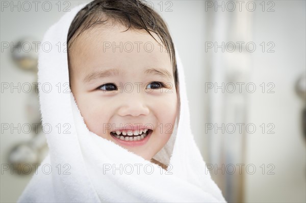 mixed-race boy having fun at the water park with white towel on his head