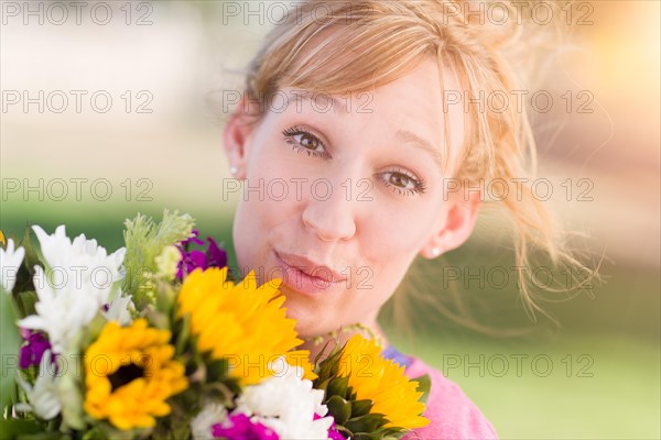 Outdoor portrait of an excited young adult brown eyed woman holding a bouquet of flowers