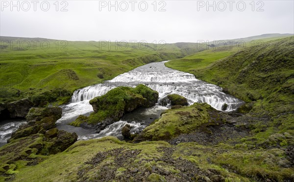 Wide waterfall between green meadows