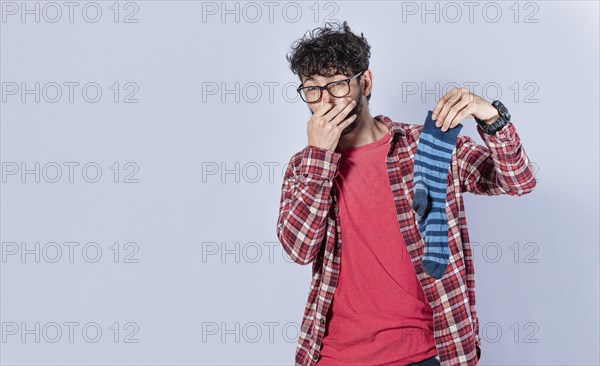 A man with a sock in his hand covering his nose
