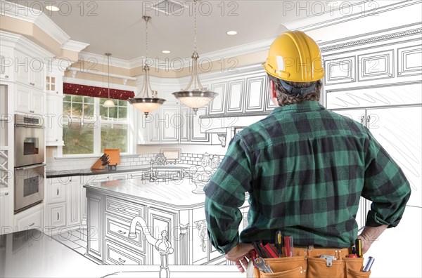 Male contractor with hard hat and tool belt looking at custom kitchen drawing photo combination on white