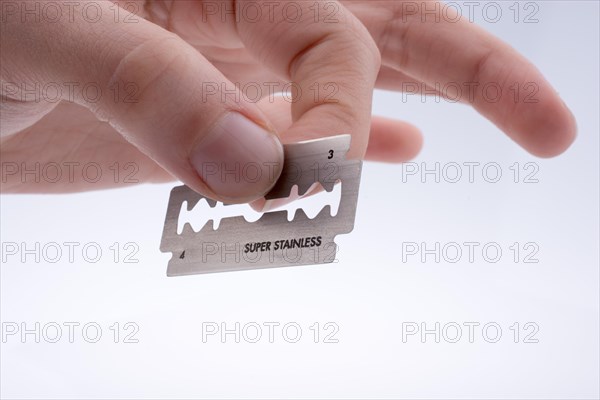 Hand holding a razor blade on a white background