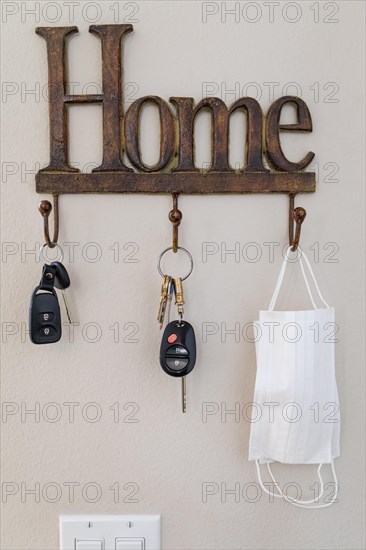 Home key hanger rack next to door with keys and medical face mask during coronavirus pandemic