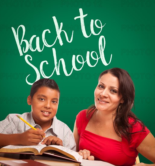 Back to school written on chalk board behind hispanic young boy and famale adult studying