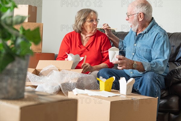 Senior couple enjoying chinese food surrounded by moving boxes
