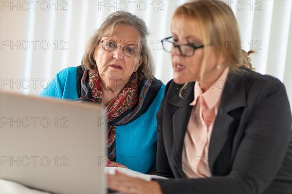 Woman helping senior adult lady on laptop computer