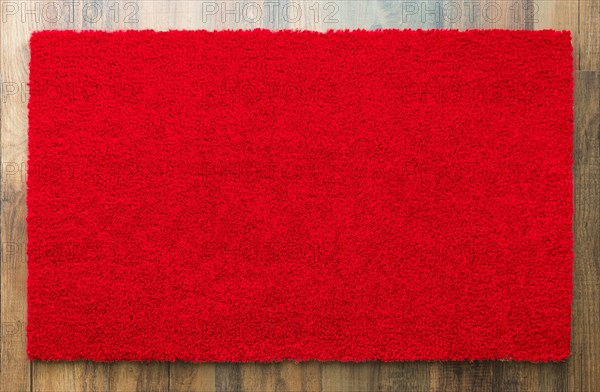 Blank red welcome mat on wood floor background ready for your own text