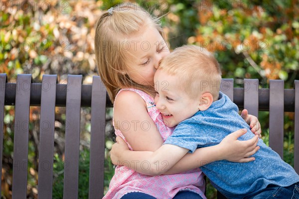 Young sister and brother having fun on the bench at the park