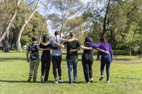 Multi ethnic family group walking arm in arm in a park. Family