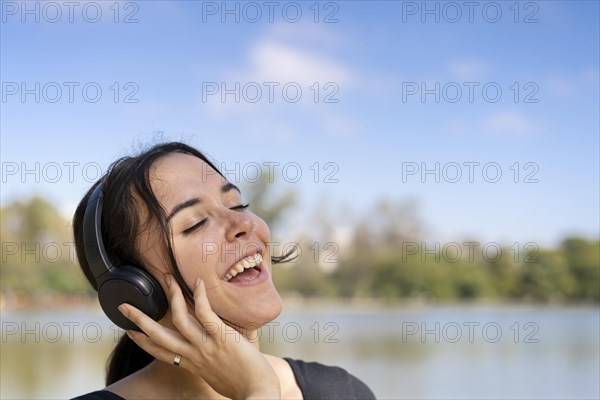 Young woman listening to music outdoors with headphones. Expression of happiness