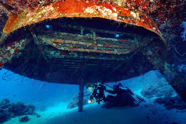 Diver with underwater lamp swimming under Jacques-Yves Cousteau's underwater house from underwater settlement Precontinent II from 1963