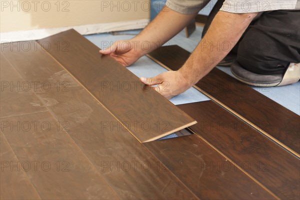 Man installing new laminate wood flooring abstract