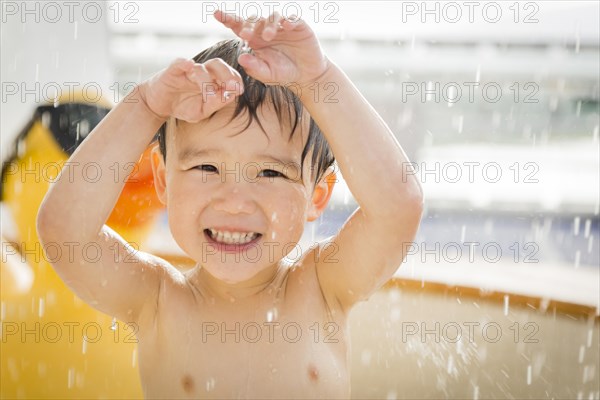 mixed-race boy having fun at the water park with large rubber duck in the background