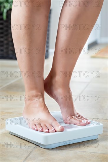 Woman standing on weight scale at home