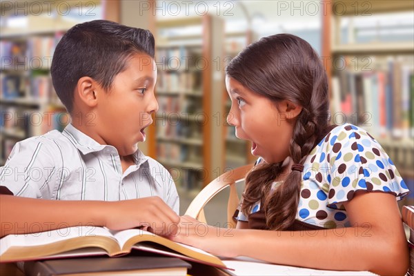 Hispanic boy and girl having fun studying together in the library