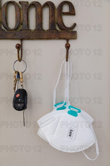 Home key hanger rack next to door with keys and medical face mask during coronavirus pandemic