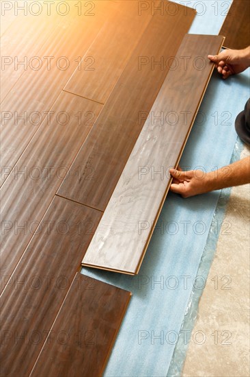 Man installing new laminate wood flooring abstract