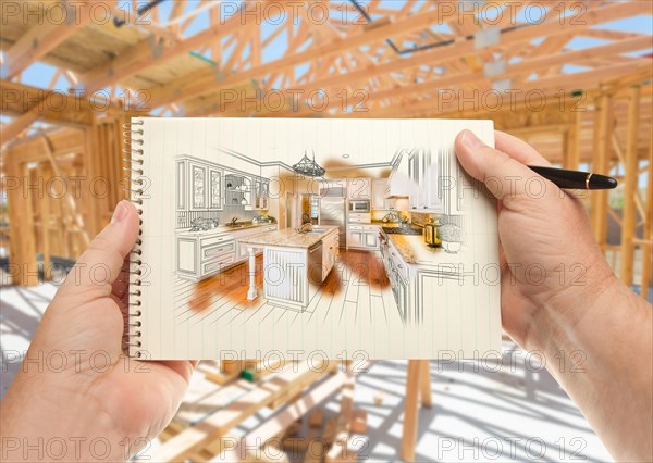 Male hands holding pen and pad of paper with custom kitchen illustration inside construction framing