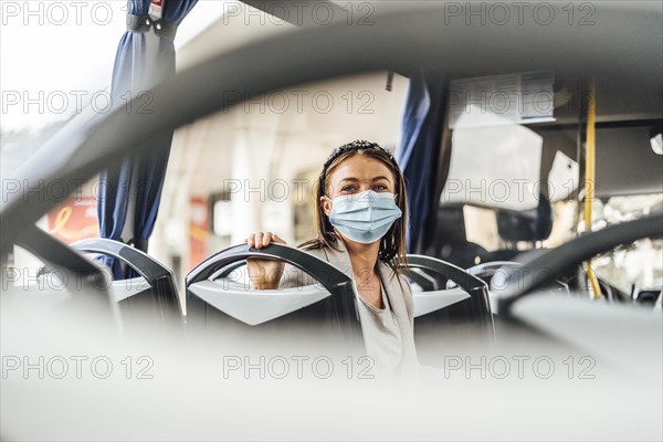 A young woman wearing protective mask commuting by the public bus