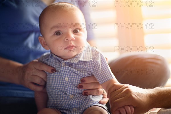 Happy mixed-race couple enjoying their newborn son in the light of the window