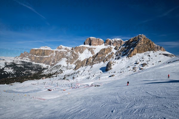 View of a ski resort piste with people skiing in Dolomites in Italy