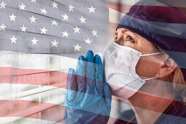 Prayerful stressed female doctor or nurse on break at window wearing medical face mask