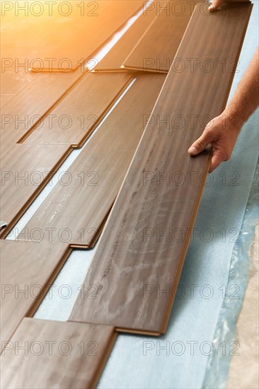 Man installing new laminate wood flooring abstract