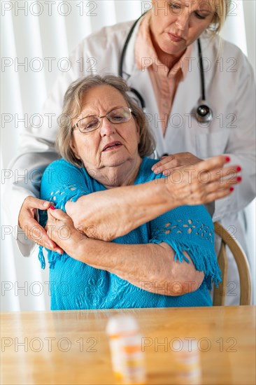 Female doctor helping senior adult woman with arm exercises