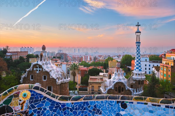 Barcelona city view from Guell Park with colorful mosaic buildings in tourist attraction Park Guell in the morning on sunrise