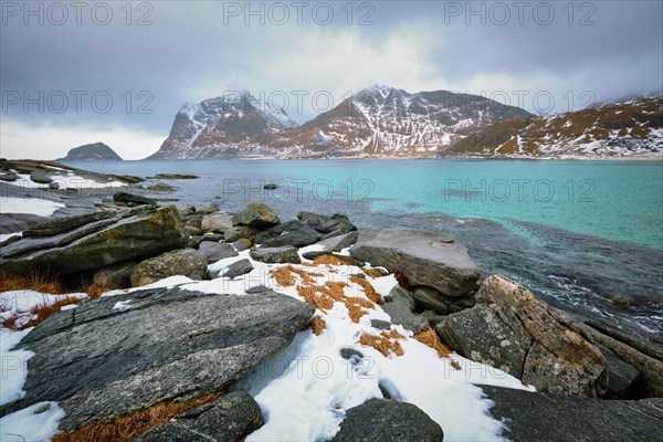 Rocky coast of fjord of Norwegian sea in winter with snow. Haukland beach