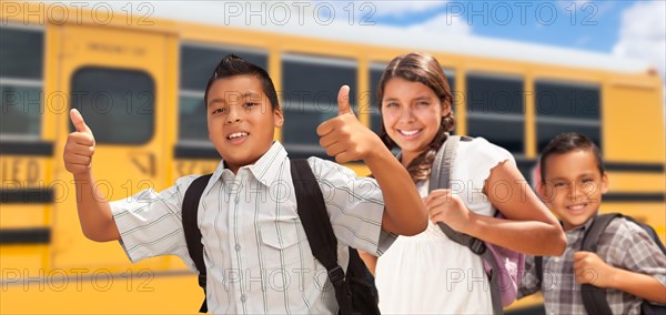 Young hispanic boys and girl walking near school bus