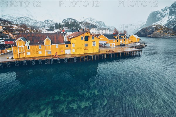 Panorama of Nusfjord authentic fishing village with yellow rorbu houses in Norwegian fjord in winter. Lofoten islands