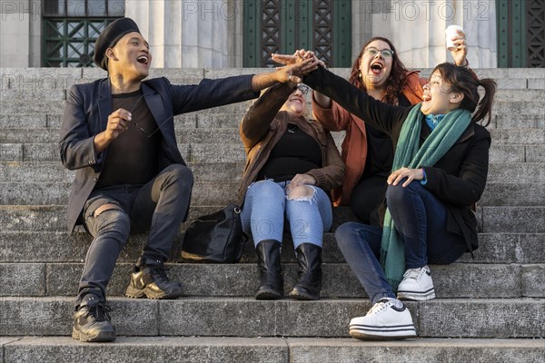 Multi ethnic group of friends sitting on some stairs having a good time chatting and laughing