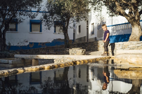 A small boy enjoying a historic square with water source in Ericeira