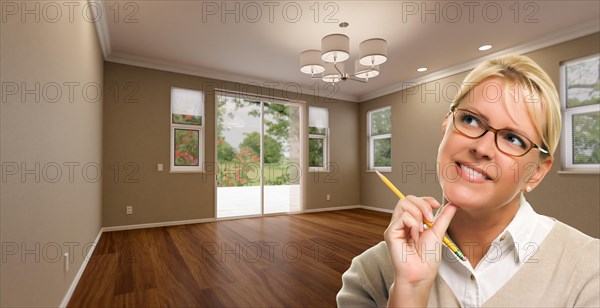 Creative woman with pencil contemplating empty room of house