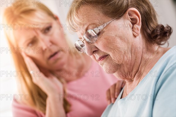 Young adult woman consoles sad senior adult female