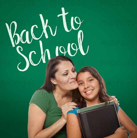 Back to school written on chalk board behind proud hispanic mother and daughter student