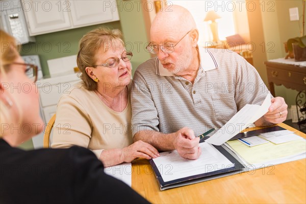 Senior adult couple going over documents in their home with agent at signing