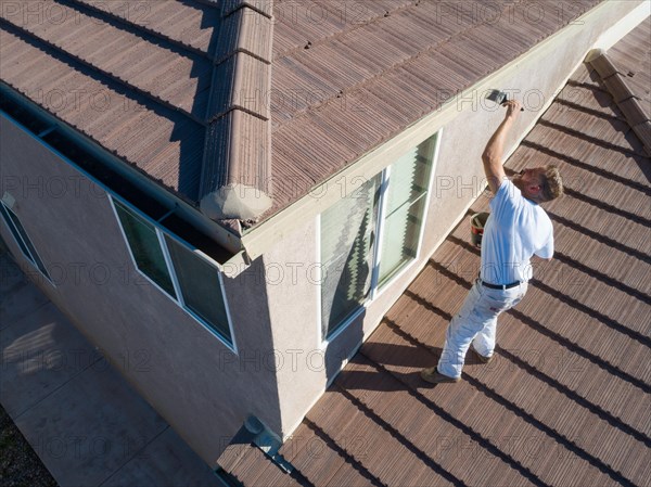 Professional painter using A brush to paint house facade