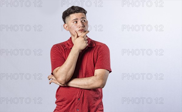 Young man wondering with his hand on his chin on an isolated background