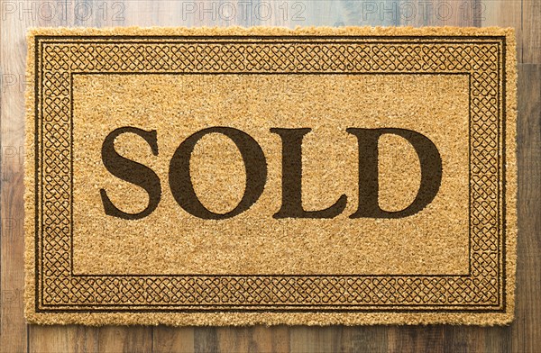 Sold welcome mat on A wood floor background
