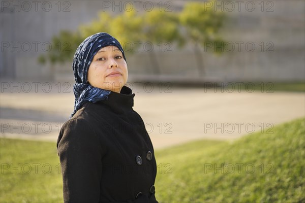 Portrait of a Latin woman undergoing cancer treatment with her head covered by a scarf with an expression of strength